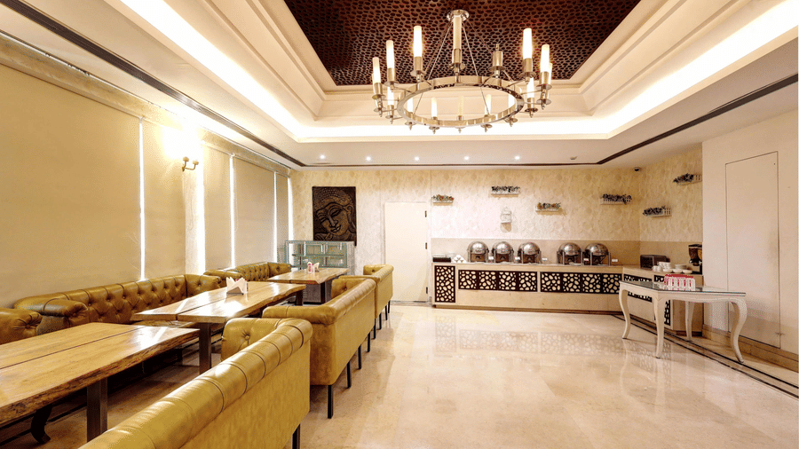 An expansive dining hall with polished cream floors, a grand circular chandelier, and rows of mustard-colored cushioned bench seating - Flute Boutique By Hotel 91, Jaipur
