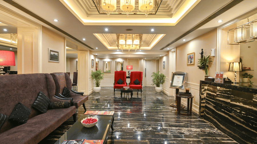A grand view of the hotel lobby showing a long plush sofa, marble floors, and elegant golden lighting fixtures in the recessed ceiling - Flute Boutique By Hotel 91, Jaipur