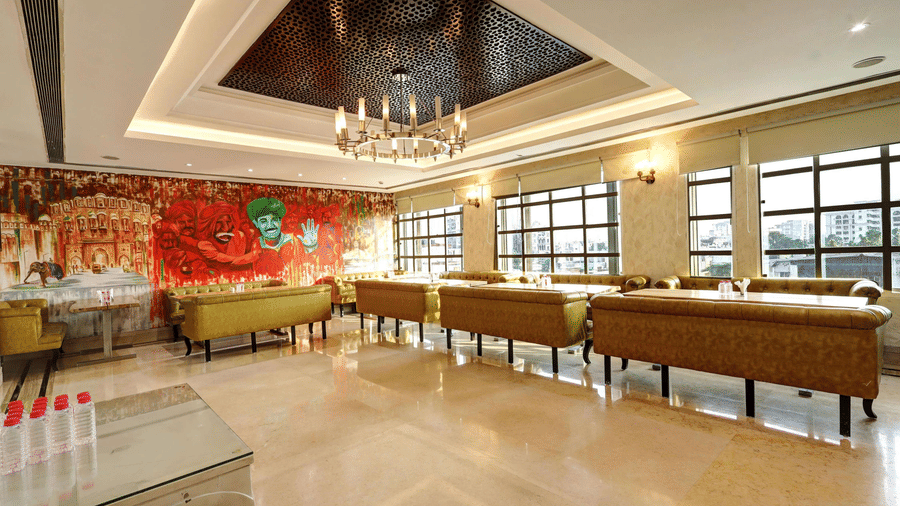 A bright restaurant space showcasing a decorative recessed ceiling, elegant chandeliers, and a colourful wall mural in the background - Flute Boutique By Hotel 91, Jaipur