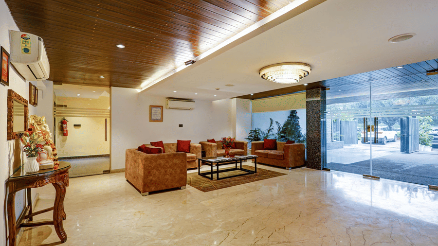A spacious hotel lobby featuring polished marble floors, comfortable brown leather sofas, and a warm wood-panelled ceiling - Hotel 91 HUDA City Centre, Gurugram