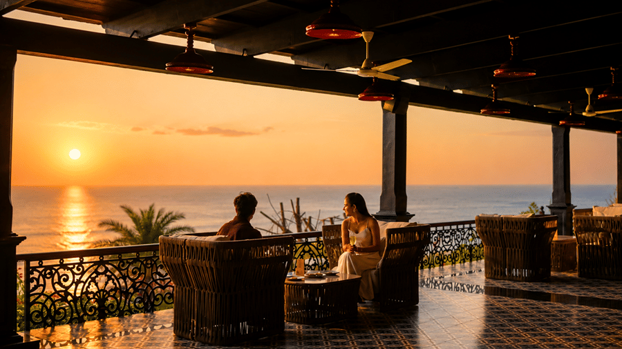 Guests relaxing at a covered outdoor balcony seating area overlooking the ocean during sunset at MAYFAIR Palm Beach Resort, Gopalpur-on-Sea.