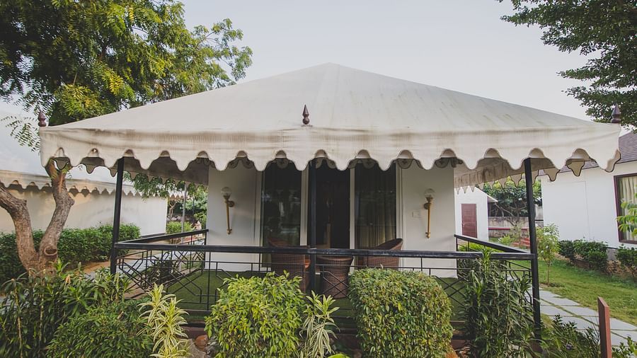 Facade of Royal Luxury Tent with Balcony surrounded by plants and trees at Rajasthali Resort & Spa Jaipur. 