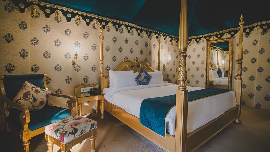 Royal Luxury Tent with Balcony with a bed and a sofa with table on the side at Rajasthali Resort and Spa.