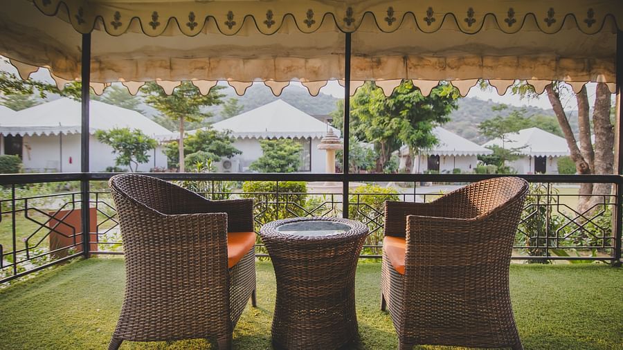 Image of a balcony with a two chairs and a table in between at Rajasthali Resort & Spa Jaipur.