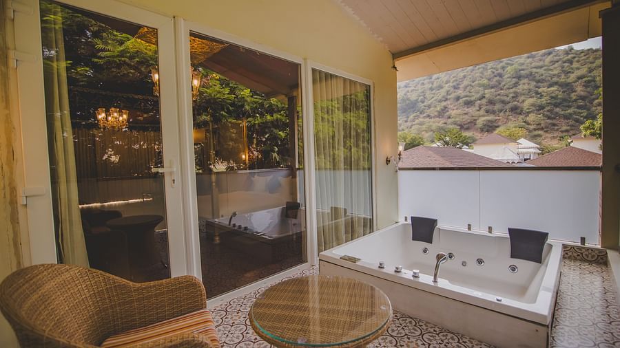 Image of a Jacuzzi with flower petals and a chair on the side at Rajasthali Resort & Spa Jaipur.