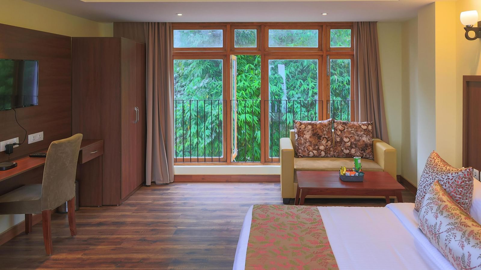 a spacious Premier Plus room at Yashshree Karbari Resort & Spa, Yangang featuring huge windows with lush greenery outside