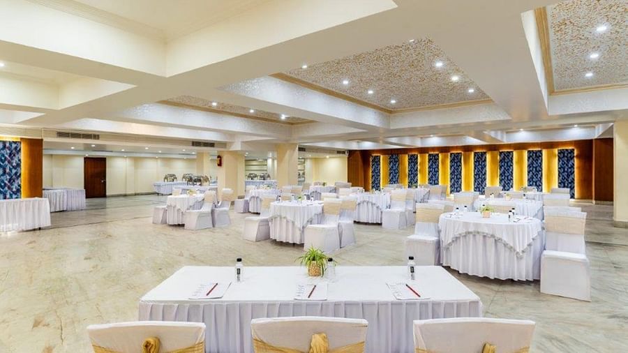 Banquet hall setup with round tables and white covers at Golden Tulip, Udaipur.