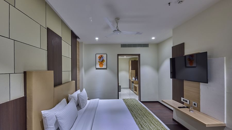 A king bed with a painting in the background in the deluxe room at Grand Continent - A Sarovar Premiere Affiliate Hotel, Hosur