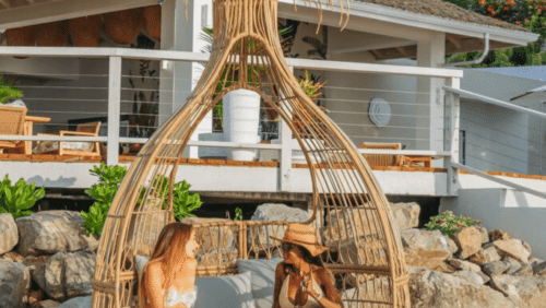 A person is relaxing in a rustic, open-air beach hut made of natural materials.
