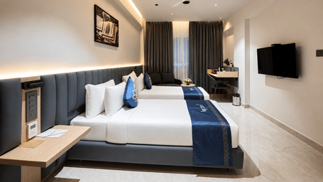 Premium Suite with twin beds and warm cove lighting along the ceiling at Hotel Kyzen, Shamshabad Airport, Hyderabad.