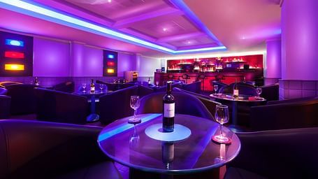 An image of a bar with illuminated purple lights at Regency Madurai by GRT Hotels