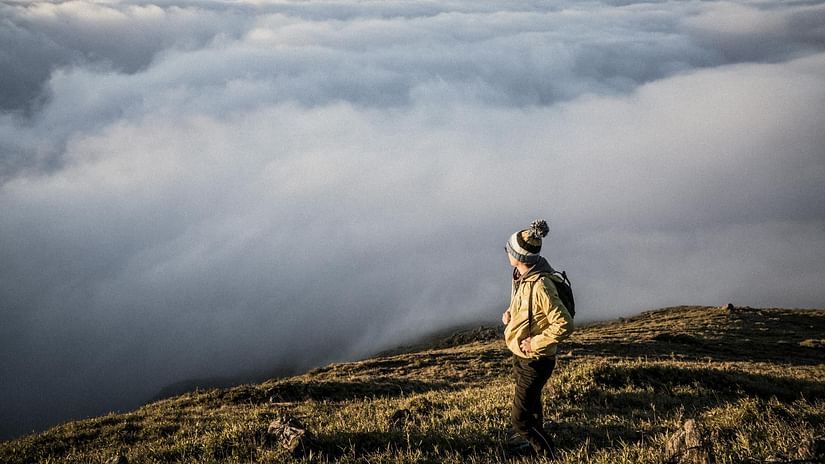 Image of a person standing on a mountain top overlooking a thick blanket of clouds - The Dukes Retreat, Khandala