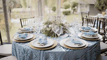 A round table set with neatly arranged cutlery and a floral centerpiece.