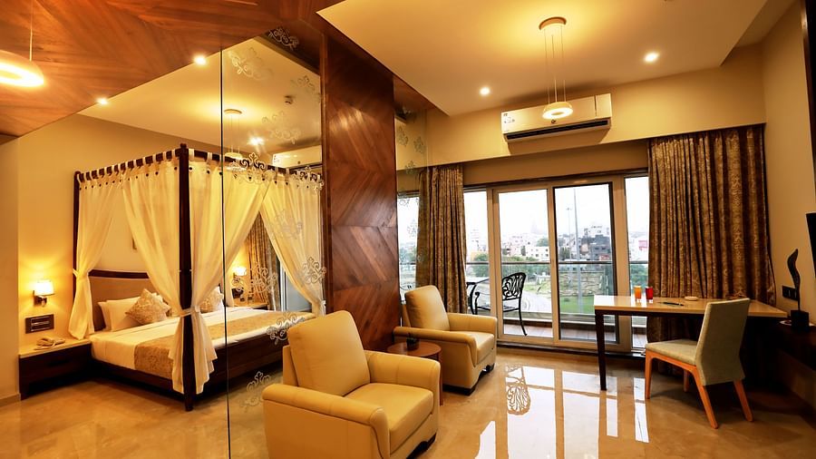 Overview of the Suite Room with a king bed, single seater sofas next to a marble wall - VITS Devbhumi, Dwarka
