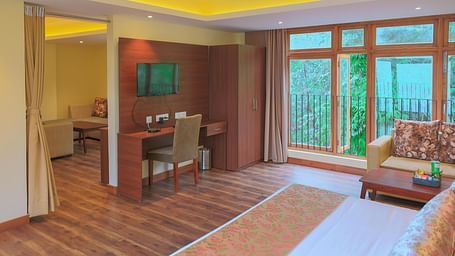 the Junior Suite with wooden flooring a huge window in the far end of the room at Yashshree Karbari Resort & Spa, Yangang