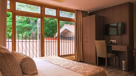 corner view image of the Premier plus room featuring a queen size bed with a wardrobe and a wall mounted television
