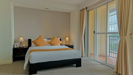 A bedroom with a bed, nightstand, and curtains | Penthouse | Central Mansions, Phnom Penh
