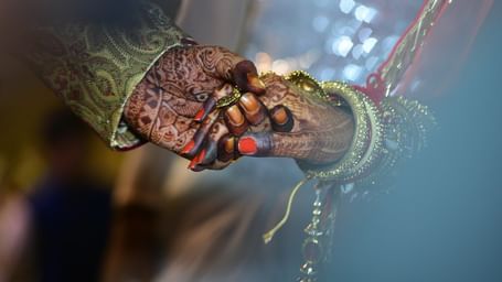A close up view of the bride and groom holding hands.