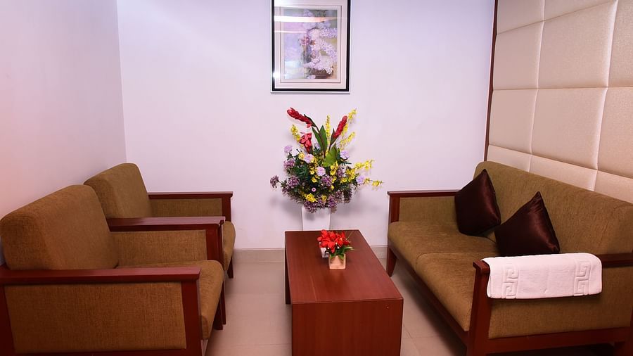 A cosy lounge area with comfortable sofas, a coffee table, and elegant decor for relaxation.- Dhanalakshmi Srinivasan Hotels, Perambalur