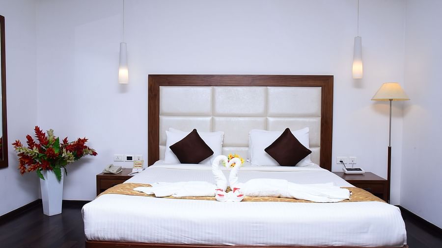 A luxurious suite featuring a king-sized bed, elegant decor, and ambient lighting for a restful retreat.- Dhanalakshmi Srinivasan Hotels, Perambalur
