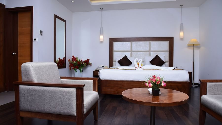 A stylish hotel suite with plush seating, warm lighting, and modern decor for a comfortable stay.- Dhanalakshmi Srinivasan Hotels, Perambalur