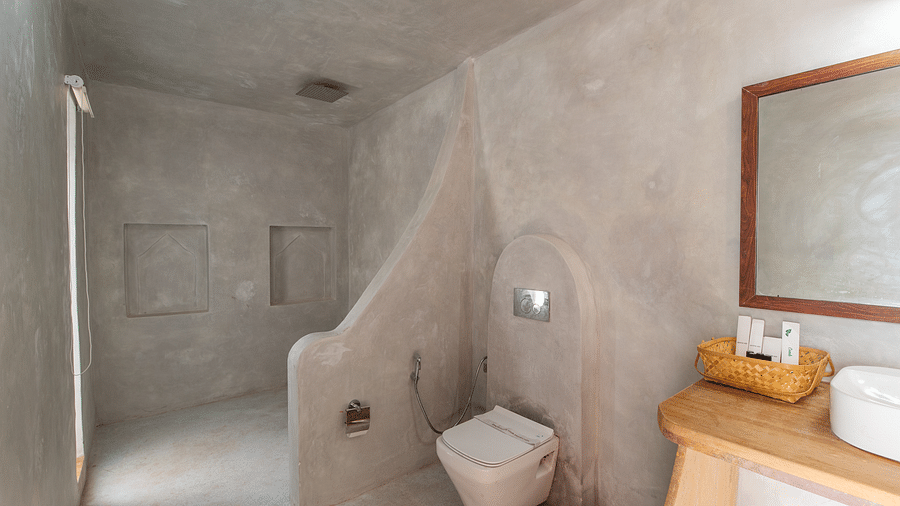 An image of a western style bathroom with a cabinet, mirror on the wall, a sink, and a commode - Karwaan Jaisalmer 