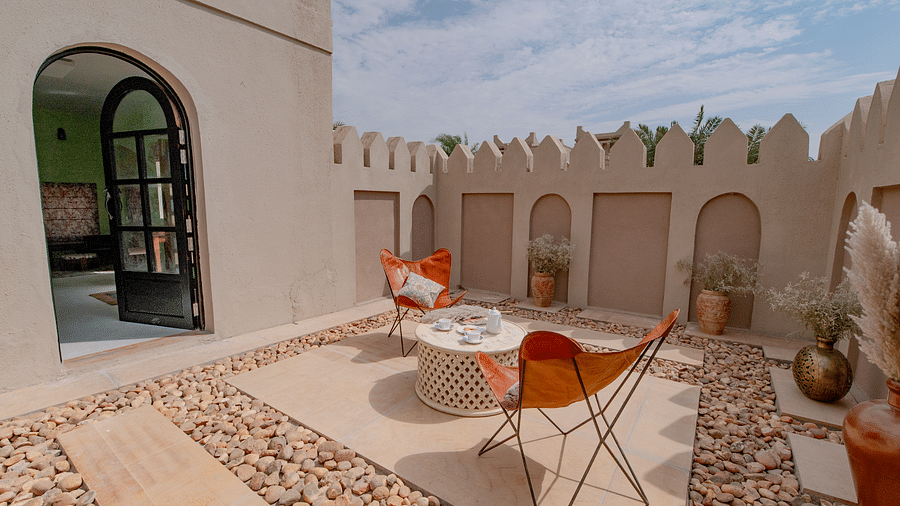 An image of an outdoor sitout area with chairs and centre table where snacks are kept - Karwaan Jaisalmer