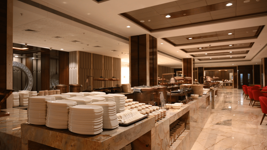 A spacious buffet area at Lambic banquet hall in Praveg's Grand Eulogia, Ahmedabad is arranged with serving stations and ample space for guests to dine comfortably.