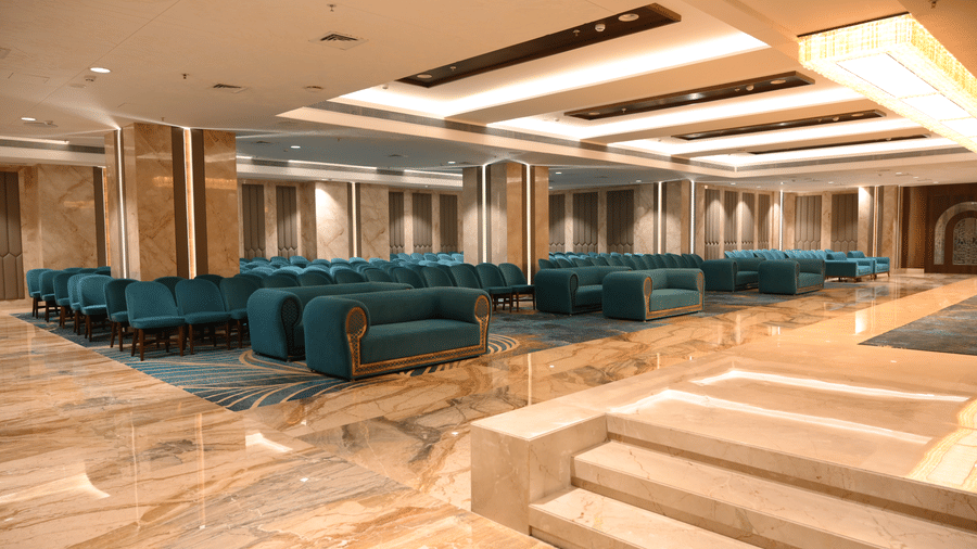 Rows of comfortable sofas face a main area next to a low set of stairs in the Marquis banquet hall at Praveg's Grand Eulogia, Ahmedabad.