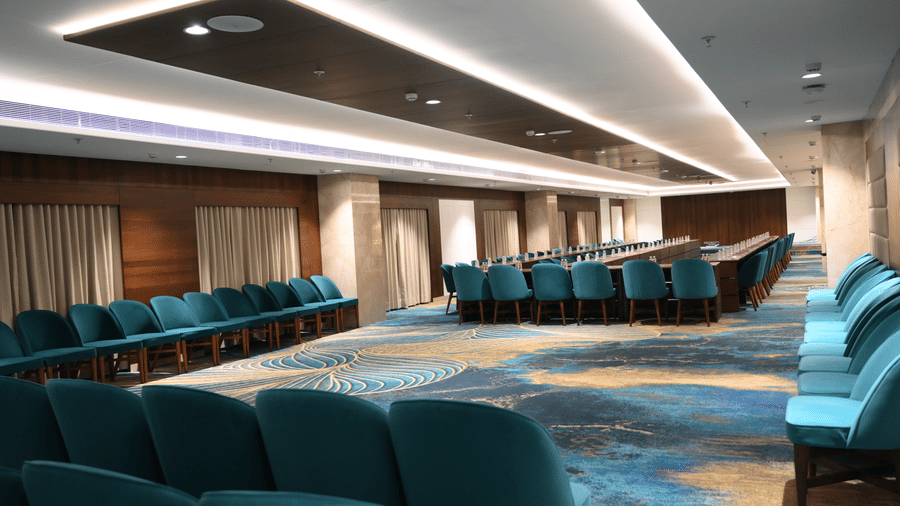 Rows of comfortable upholstered seating are neatly arranged under recessed ceiling lights in the Sky Lounge at Praveg's Grand Eulogia, Ahmedabad.