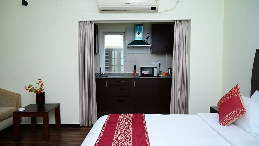 Image of a double bed with pink bedsheet and a kitchen visible from the Executive Suite at Sterling Keys by TGI