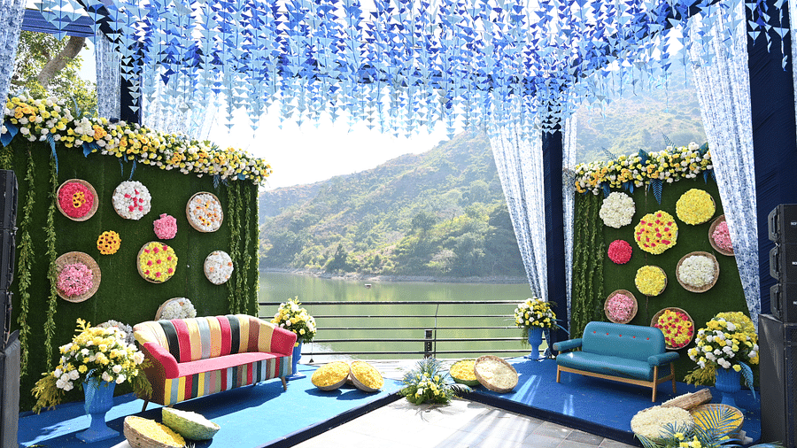 Blue floral mandap with colourful sofa seating and green hills as a backdrop - Via Lakhela Resort & Spa
