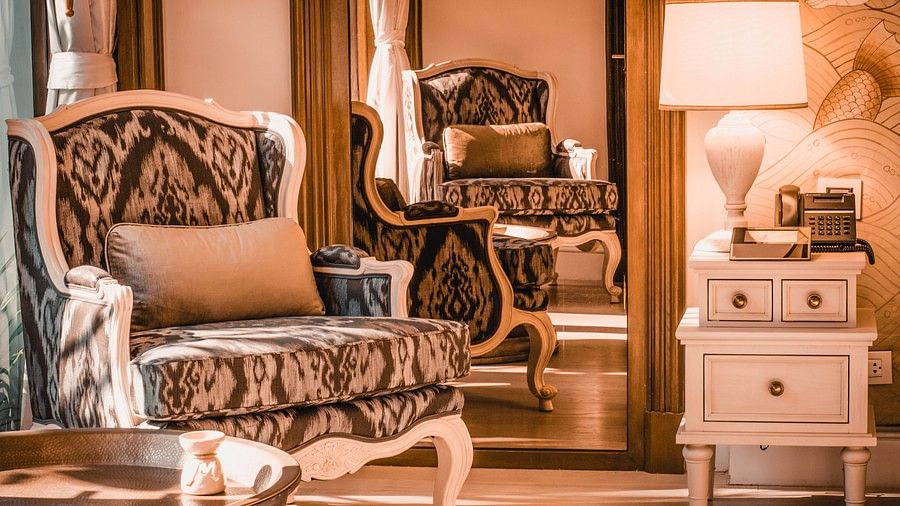 image of a patterned cushioned armchair with a mirror behind it - one bedroom private pool beachfront villa