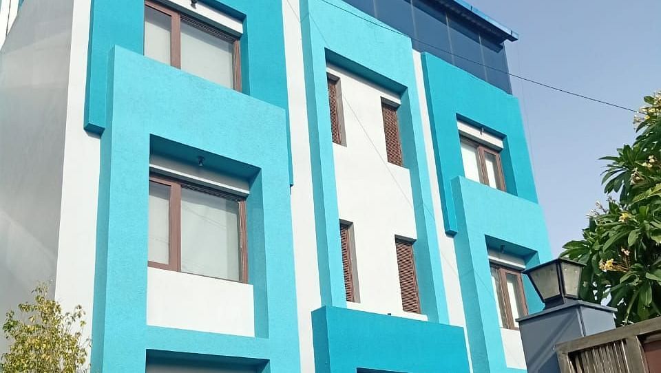 A colourful blue building with multiple windows and some greenery in front - Asian Suites IFFCO Metro, Gurgaon