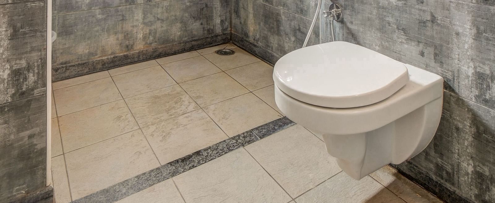 A spacious washroom at Harigovinda's JNStay, featuring a western toilet and a shower area