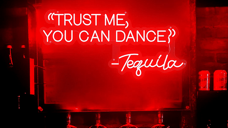 An image of a poster reading Trust me you can dance on the board illuminated by red lights - Motel Divine International, Roorkee