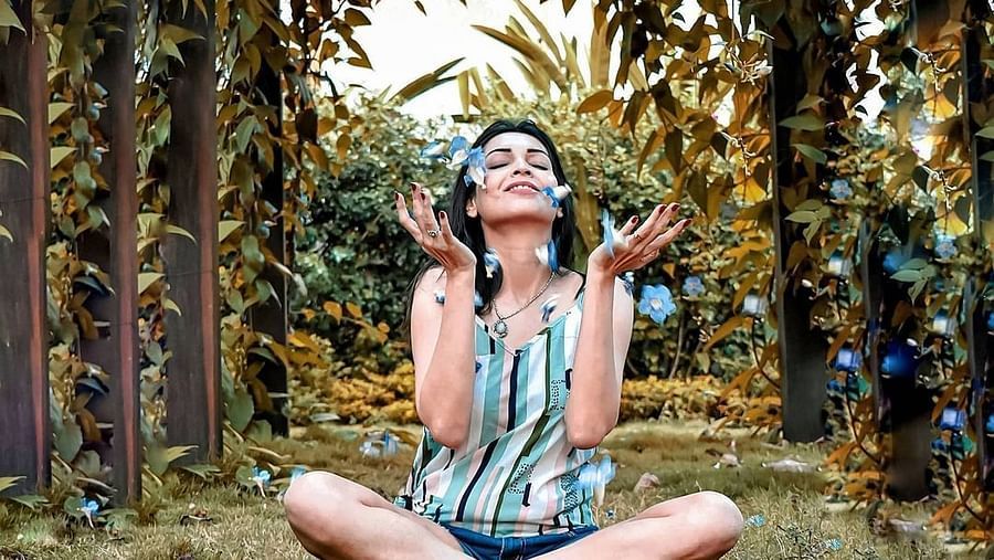 an image of a Woman elated as blue flowers fall on her - Rhythm Lonavala