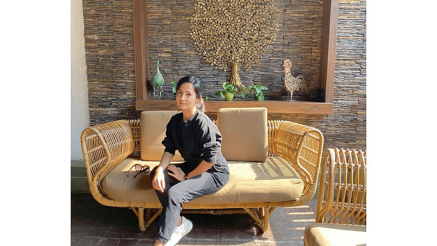 Woman in black shirt and pants sitting on a cream coloured sofa - Rhythm Lonavala