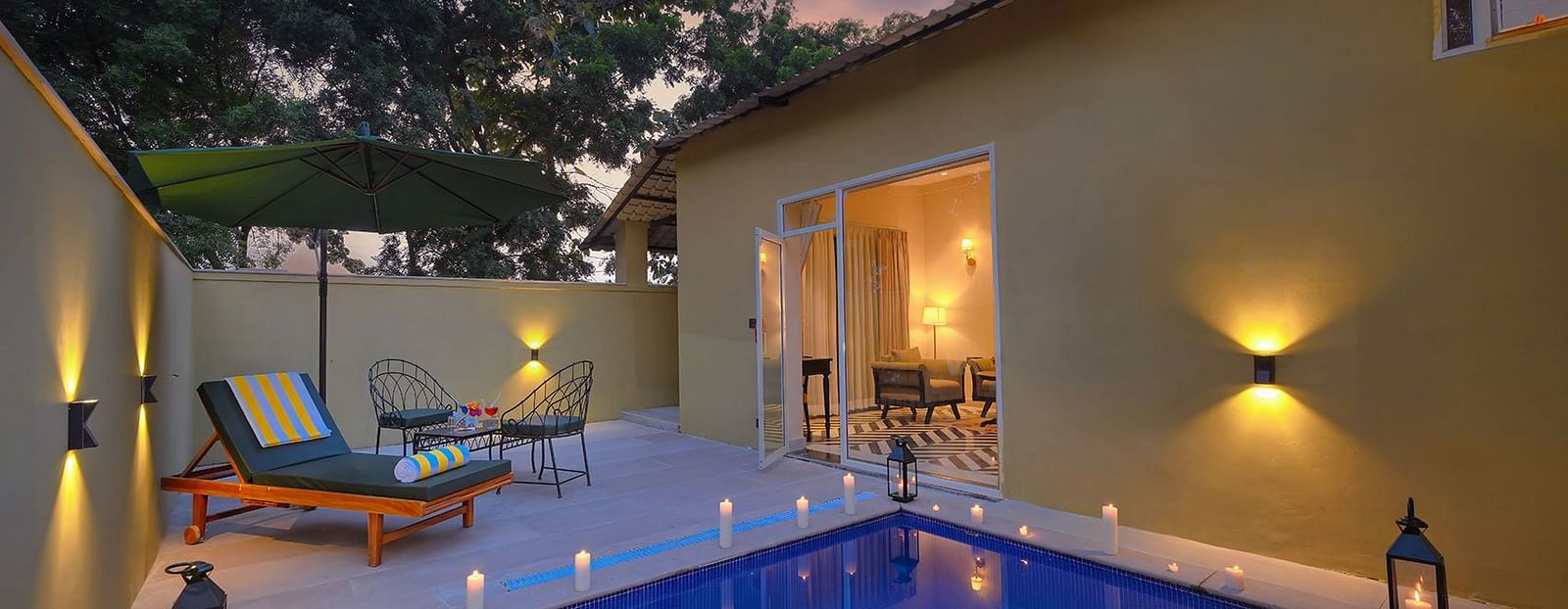 Luxury Suite Cottage with a small, illuminated private pool, lounge chairs, and an open doorway showing the interior at twilight - Singhvilas, Ranthambore
