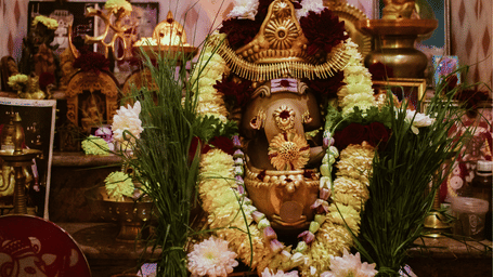 Lord ganesha decorated with flowers and a garland in a praying place. 