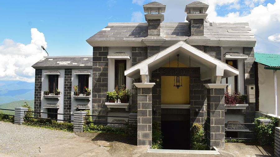 Traditional stone building with a wooden door and a balcony overlooking the mountains.