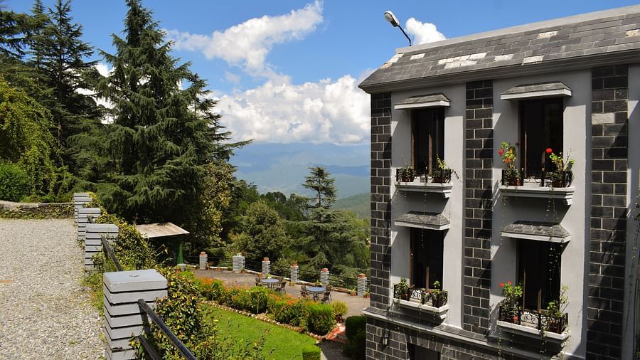 Side view of a modern hotel building with a balcony overlooking the mountains.