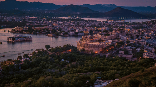 Aerial view of the city of Alwar with buildings near a lake and hills in the background