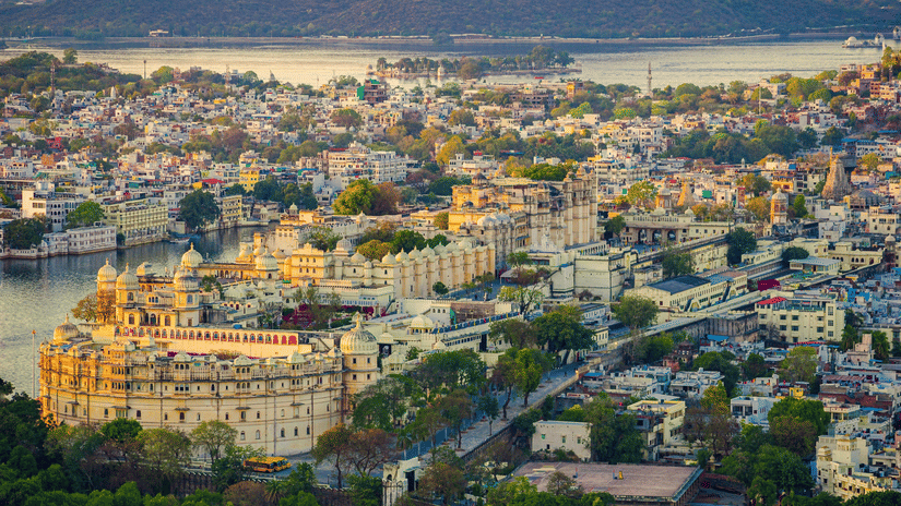 Aerial view of the city of Udaipur with the City Palace in the foreground and Lake Pichola in the backdrop.