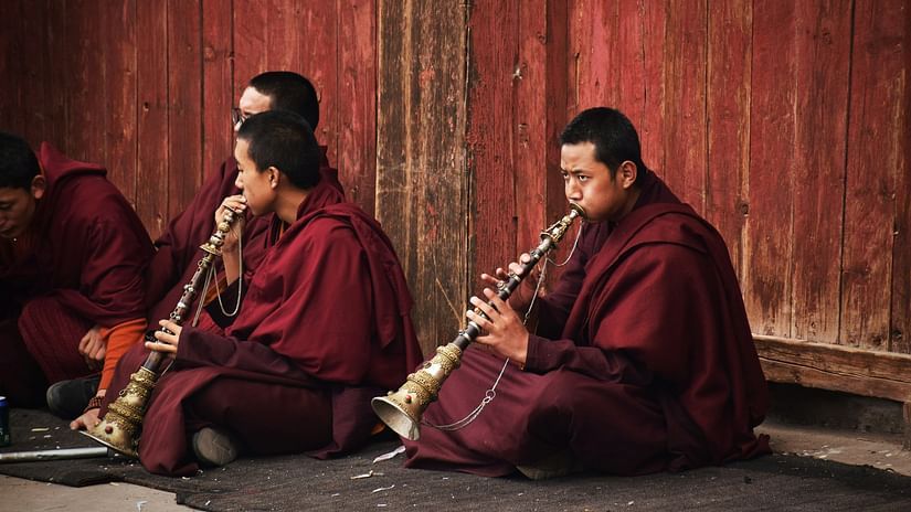 a group of Tibetians sitting on the ground playing an instrument 