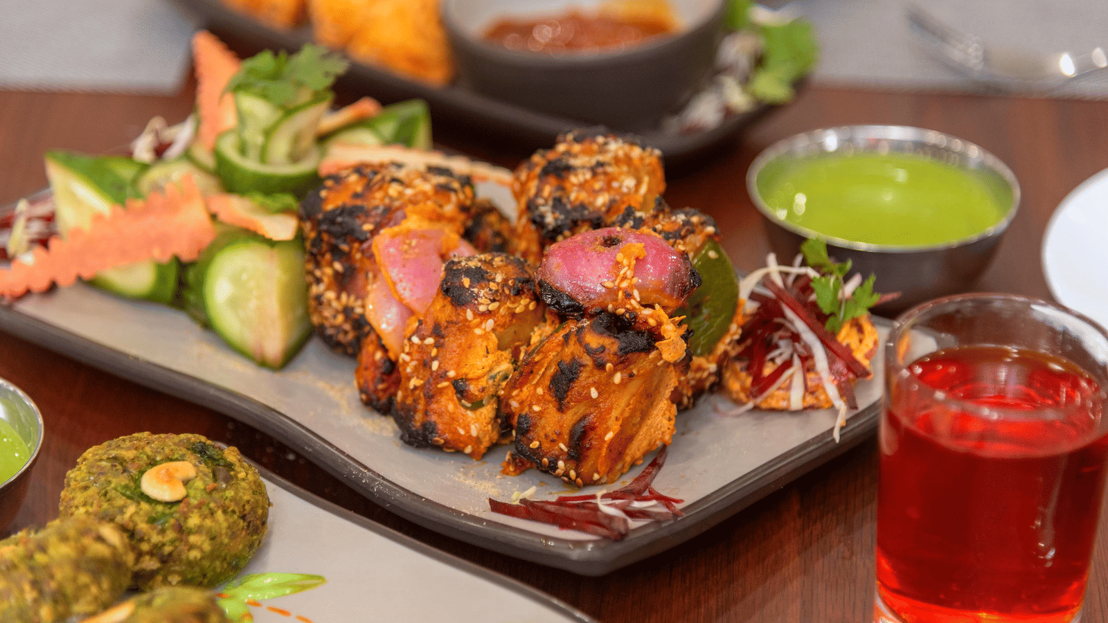 A close-up of a plate with food skewers, sliced vegetables, and a drink glass at Perfectstayz Premium Shanti Heritage, Haridwar