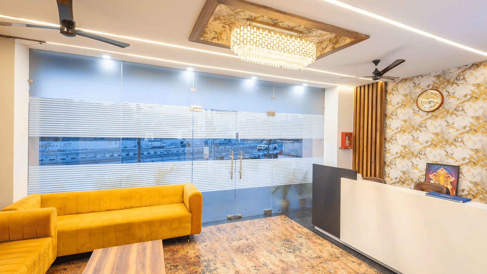 A hotel lobby showing a reception desk, a sofa seating area, and ceiling fan at Perfectstayz Premium Shanti Heritage, Haridwar