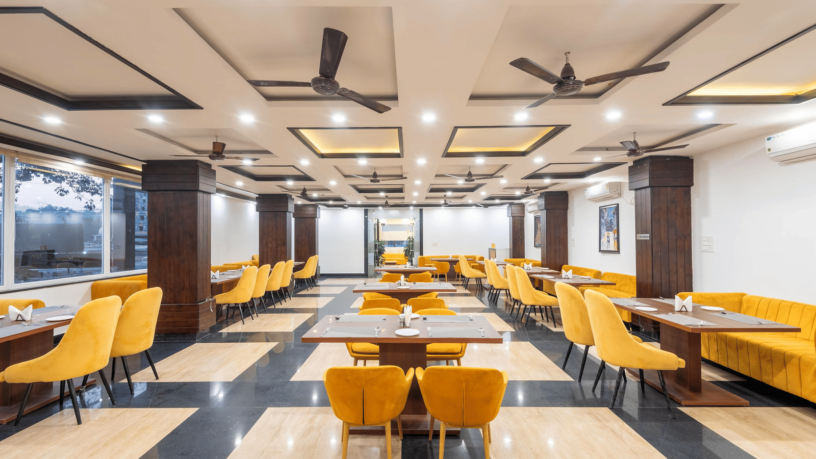 A dining area with several tables, chairs, and ceiling fans at Perfectstayz Premium Shanti Heritage, Haridwar