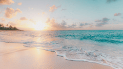 The sun rising over a calm ocean, washing gentle waves with white foam onto a sandy beach under a light blue sky with scattered clouds.