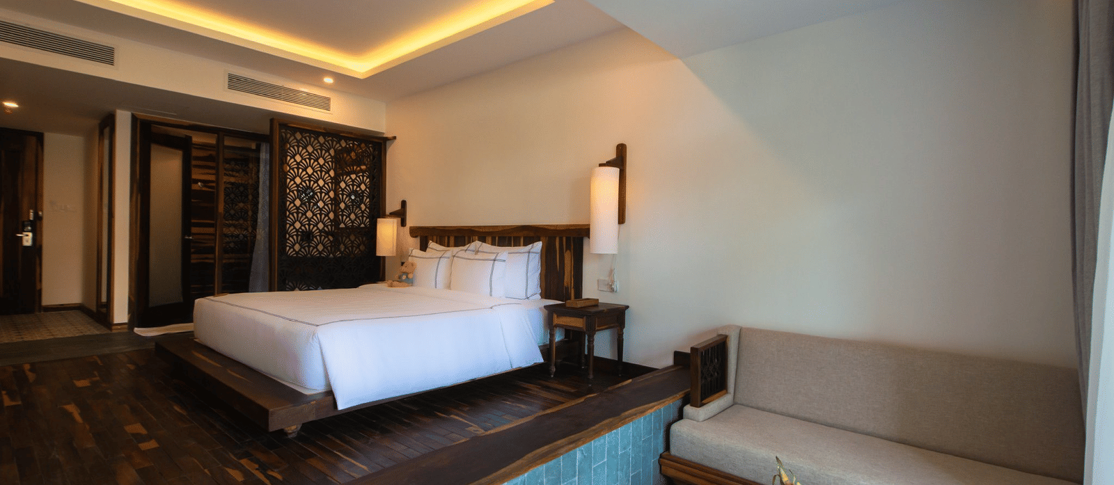 A corner view of Balcony Room with king bed, seating area, patterned tile floor, and balcony at Alibu Resort Nha Trang.